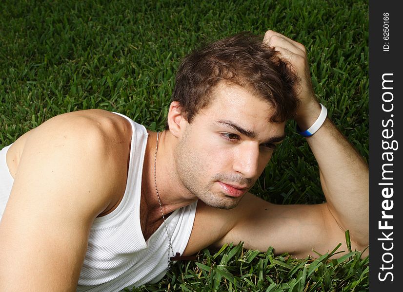 Young man laying on the grass on his side