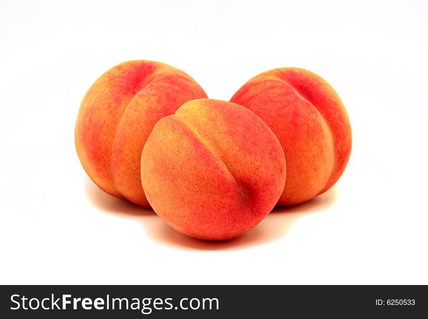 Three fresh peaches on a white background