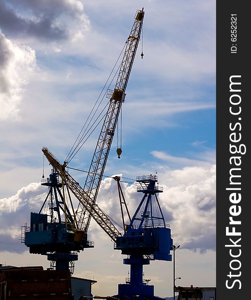 Silhouette of two Industrial yard cranes at the end of a work day. Silhouette of two Industrial yard cranes at the end of a work day