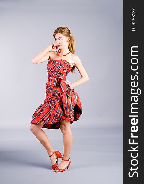 Portrait of the standing girl in red dress on gray background. Portrait of the standing girl in red dress on gray background