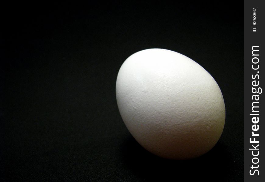 A single white egg on a black background
