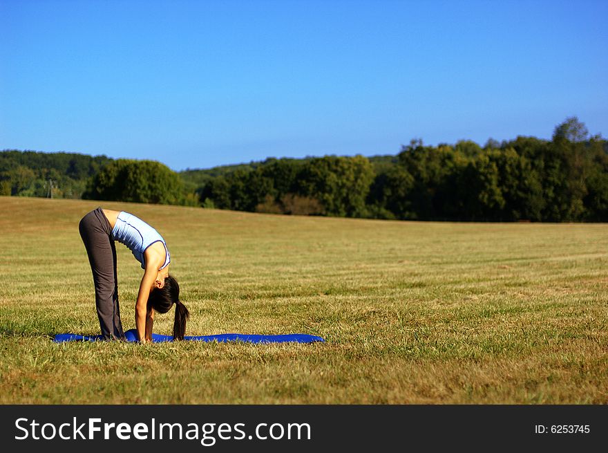 Girl practicing yoga in a summer meadow. Girl practicing yoga in a summer meadow.