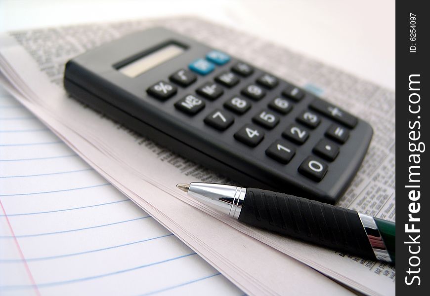 Calculator with newspaper and pen over lined paper. Calculator with newspaper and pen over lined paper