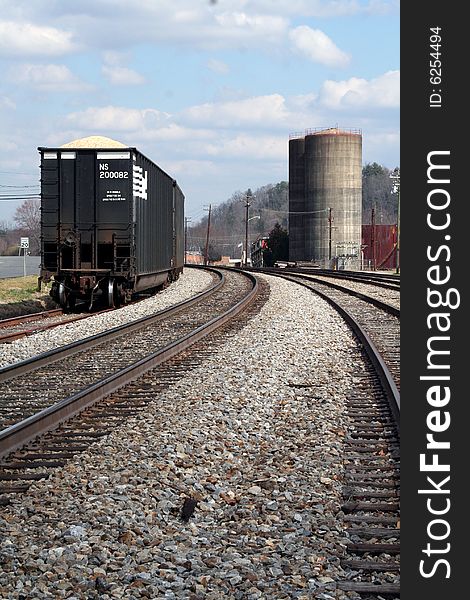 A train sitting on a railroad track beside a factory