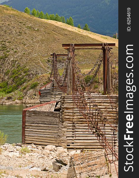 Old suspension bridge above river in mountains