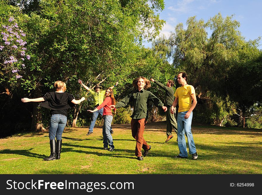 Group of six friends spinning around and jumping in a park. Group of six friends spinning around and jumping in a park