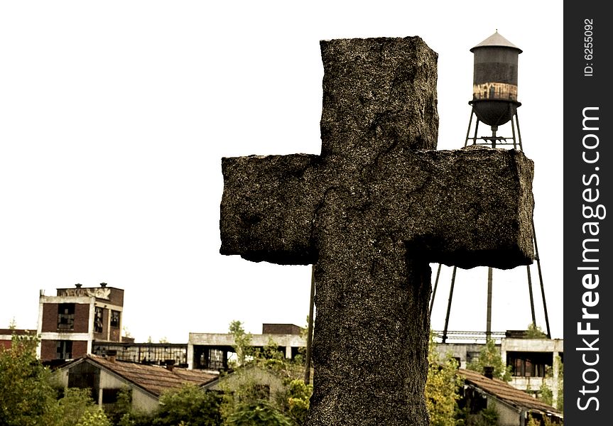 Picture of a stone cross in a cemetery with a run down factory and water tower in the background. Picture of a stone cross in a cemetery with a run down factory and water tower in the background