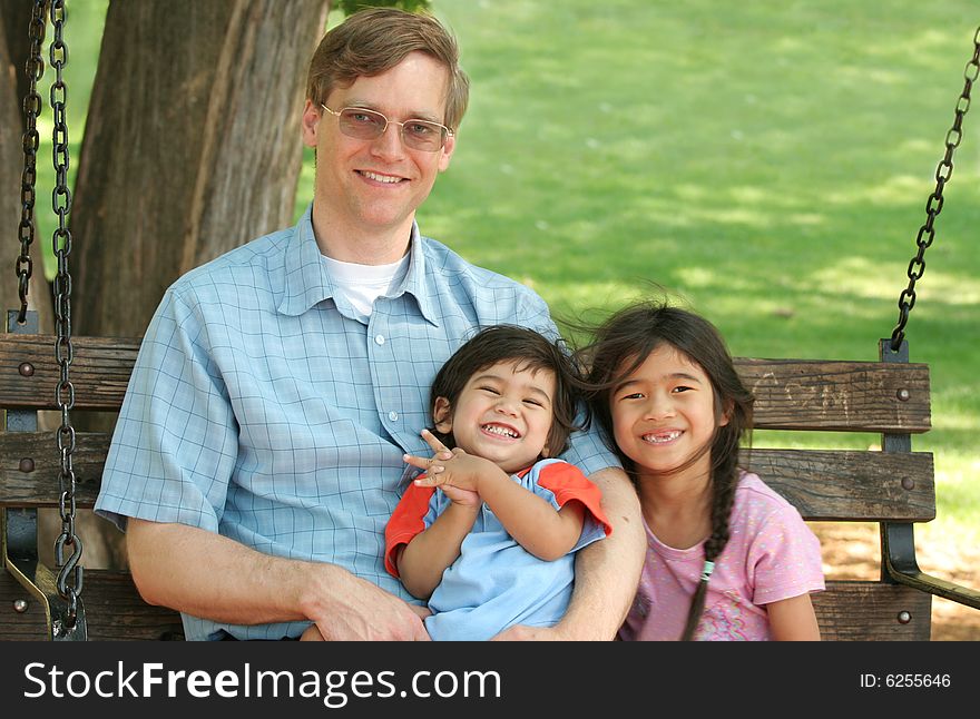 Father And Children Enjoying Swinging In The Park