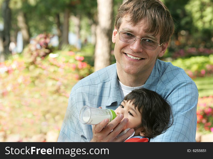 Father feeding his baby a bottle in the park