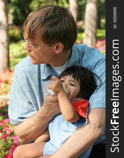 Father feeding his baby a bottle in the park