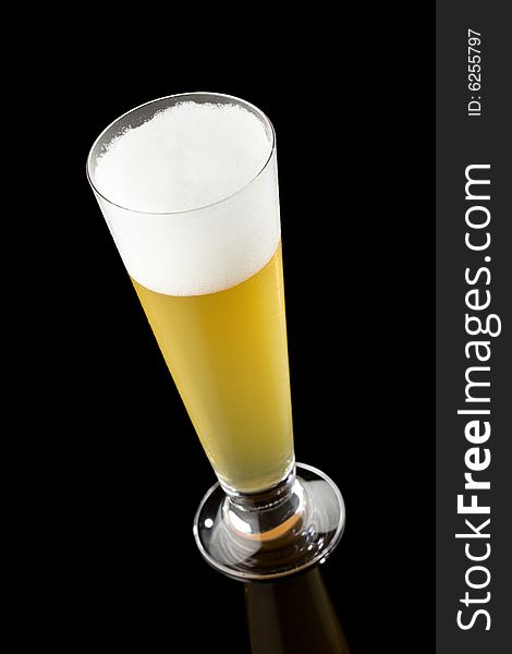 High angle view of a light beer in a tall glass isolated on a black background. High angle view of a light beer in a tall glass isolated on a black background
