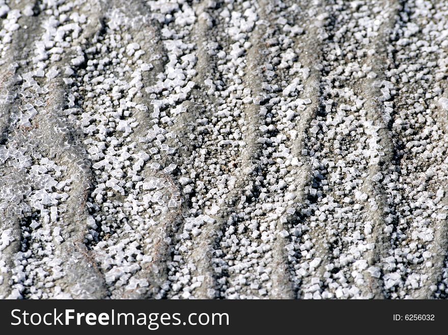 Background salt crystals on a wavy surface of grey sand