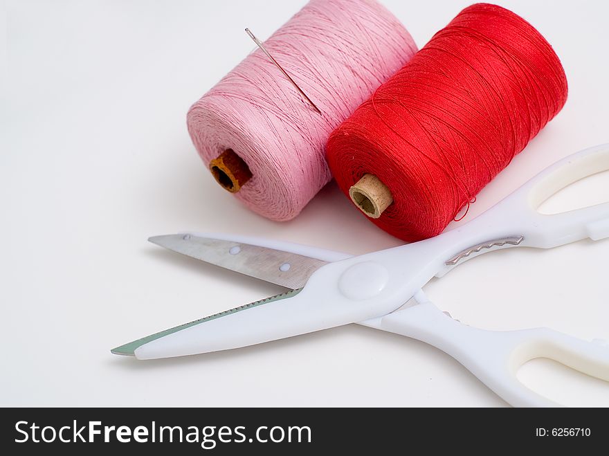 Scissors and two spools of threads at white background. Scissors and two spools of threads at white background
