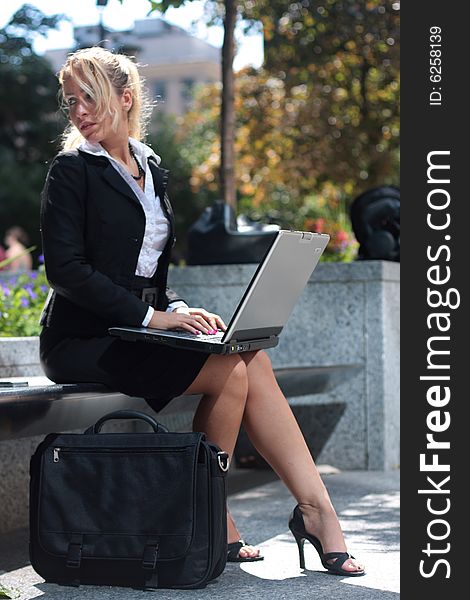 Pretty businesswomen working on a laptop outside. Pretty businesswomen working on a laptop outside