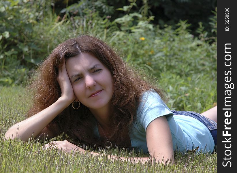 Young woman lying on the grass thinking