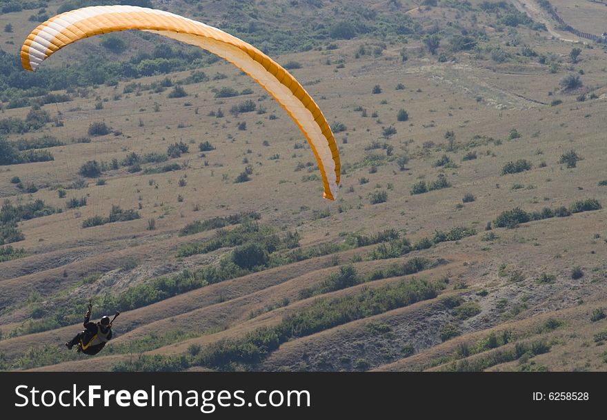 Orange paraglider above the valley