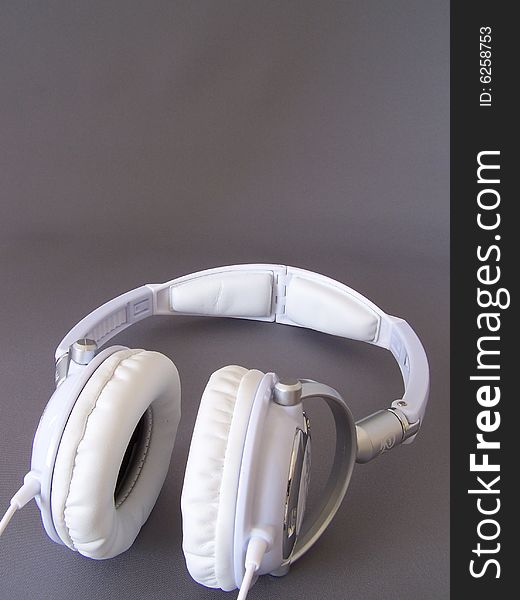 White padded headphones led on their side. White padded headphones led on their side.