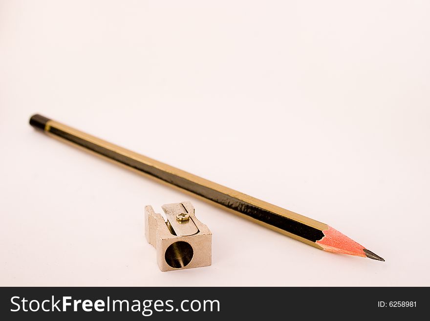 Black and gold lead pencil with a metal pencil sharpener on a white background. Black and gold lead pencil with a metal pencil sharpener on a white background