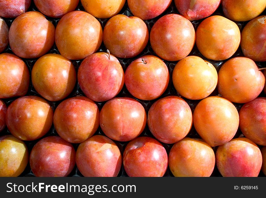 Red plums lined up in a crate. Red plums lined up in a crate