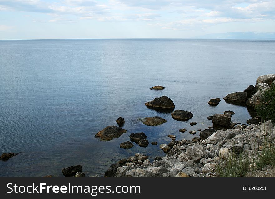 Morning sea with stones lying in water on background with sky. Morning sea with stones lying in water on background with sky