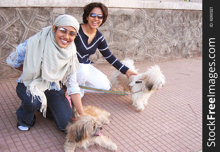 Two Indian Babes playing with Two shaggy pet dogs. Two Indian Babes playing with Two shaggy pet dogs