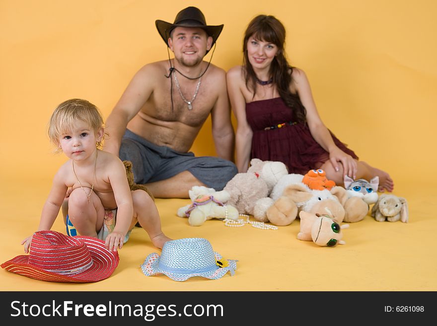 Pregnant mother, father, daughter with the hats and the toys in the studio. Pregnant mother, father, daughter with the hats and the toys in the studio