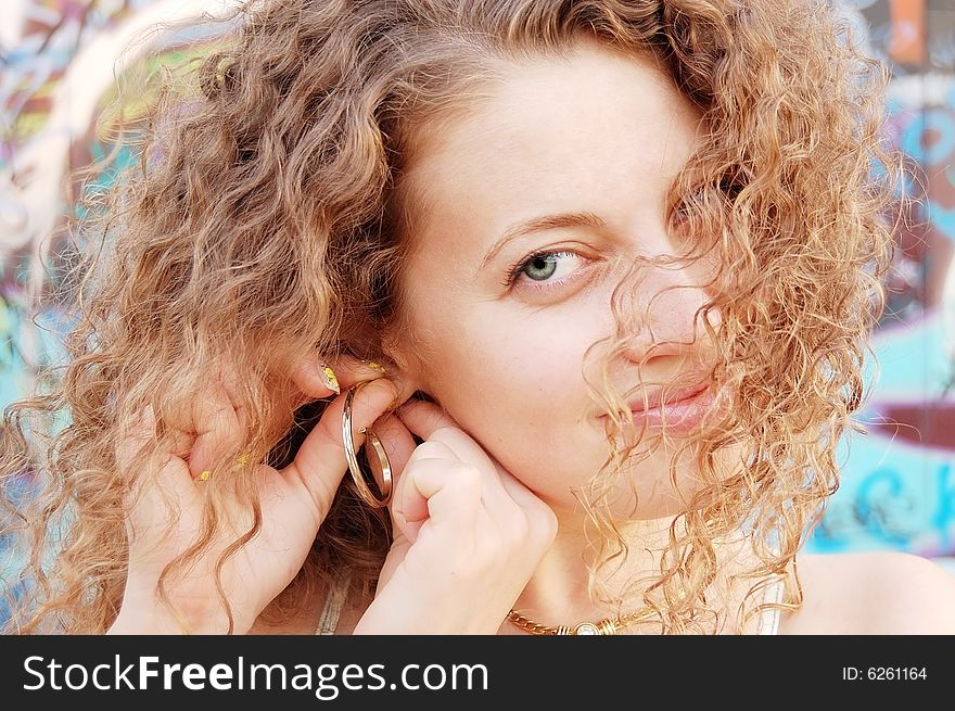 Beautiful girl with green eyes and curling blond hair  adjusting her gold ear ring. Beautiful girl with green eyes and curling blond hair  adjusting her gold ear ring