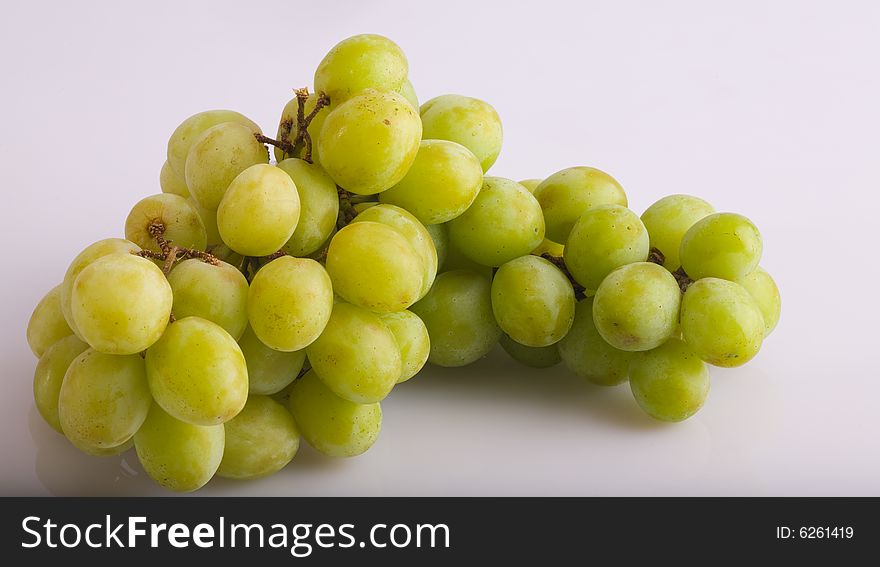 A green grape bunch on a white reflective background