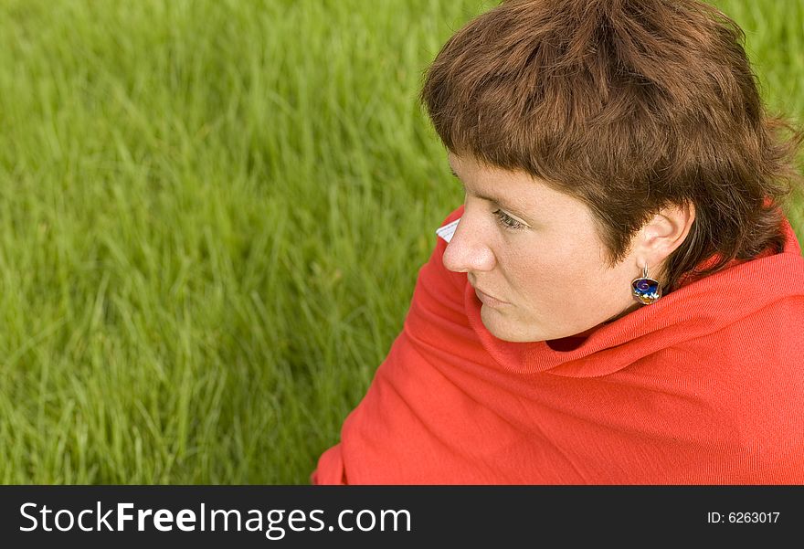 Closeup portrait of pretty redhead woman sitting on the grass