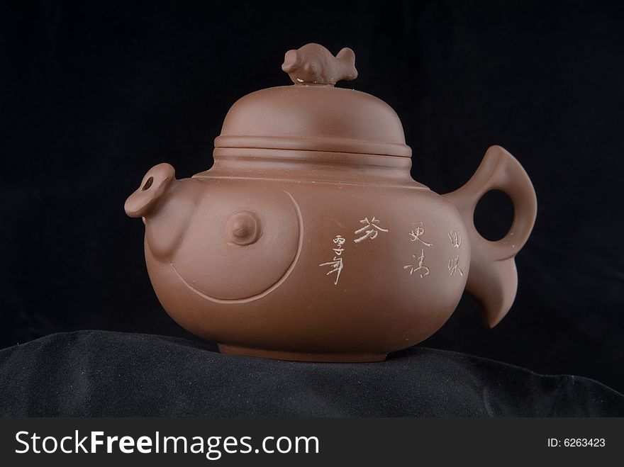 The fictile teapot is in dark background. The fictile teapot is in dark background.