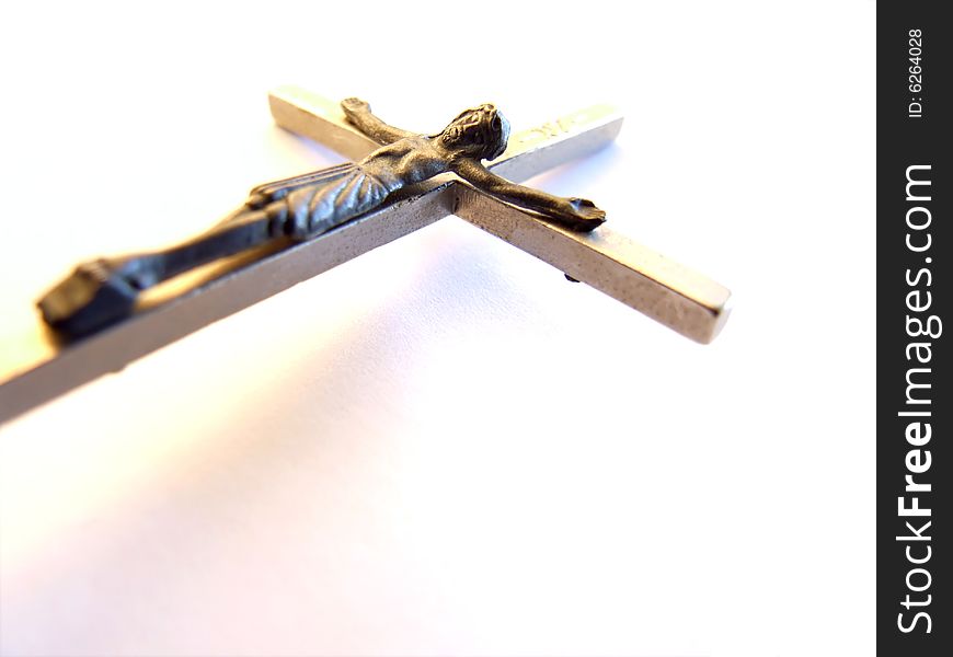 Close shot of a metal crucifix on a white background with a slight shadow. Close shot of a metal crucifix on a white background with a slight shadow.