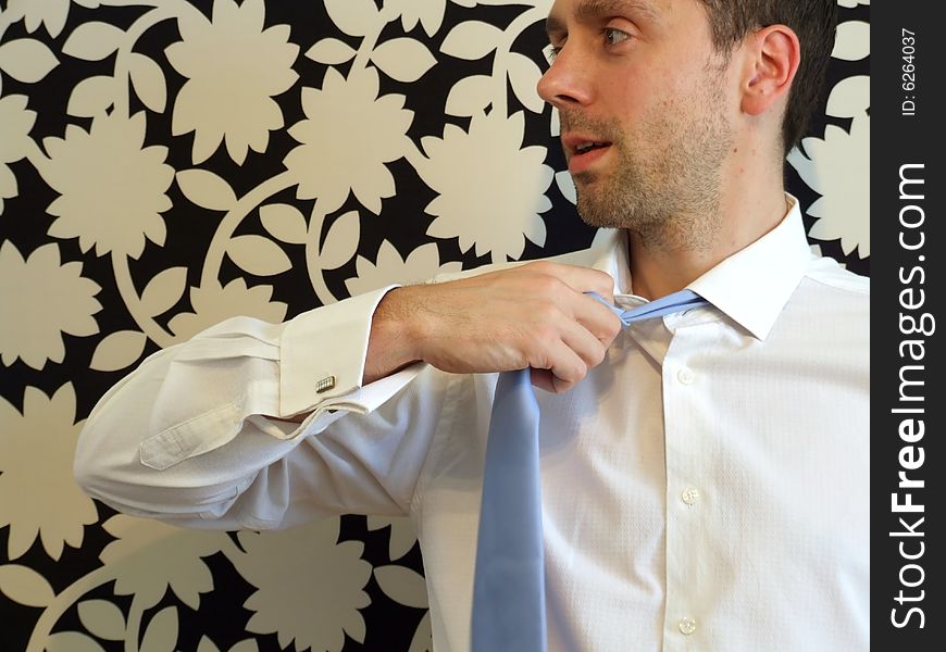 A business man removes his tie with vigour after a long day at work. on a patterned background. A business man removes his tie with vigour after a long day at work. on a patterned background.