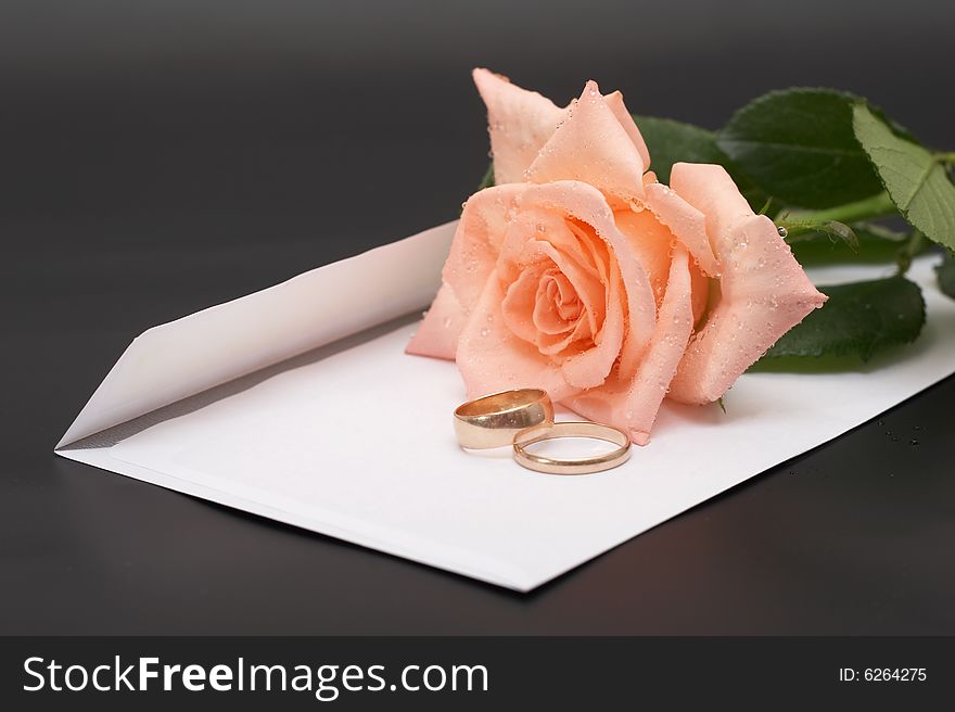 Rose, envelopes and wedding rings on a black background