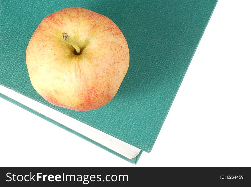 A fresh  red apple on top of a book. A fresh  red apple on top of a book