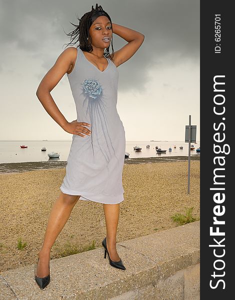 Attractive young African girl stands on sea wall