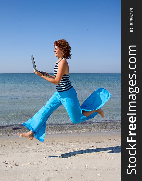 Girl with laptop running along sea coast. Girl with laptop running along sea coast