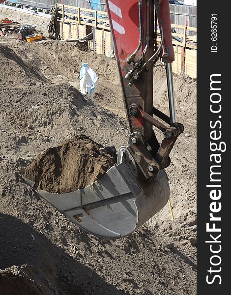 Excavator bucket on construction site digging up dirt