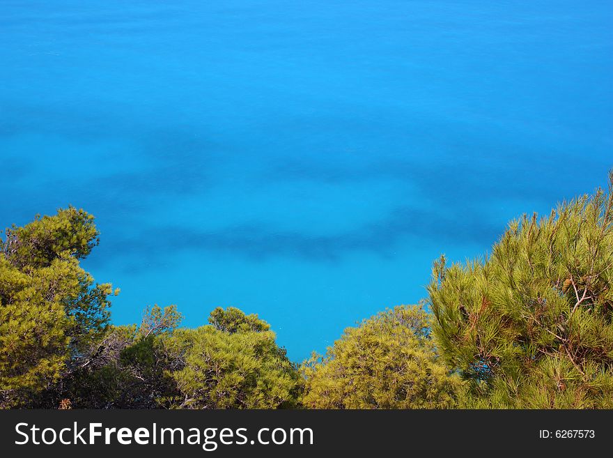 A turquoise aagainst the green pines at the western coast of Lefkada island (Pefkakia area), at the Ionian sea, Greece. A turquoise aagainst the green pines at the western coast of Lefkada island (Pefkakia area), at the Ionian sea, Greece