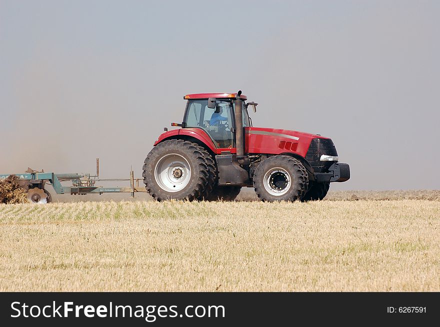 Large tractor pulling plow, throwing dust up in the air. Ukraine