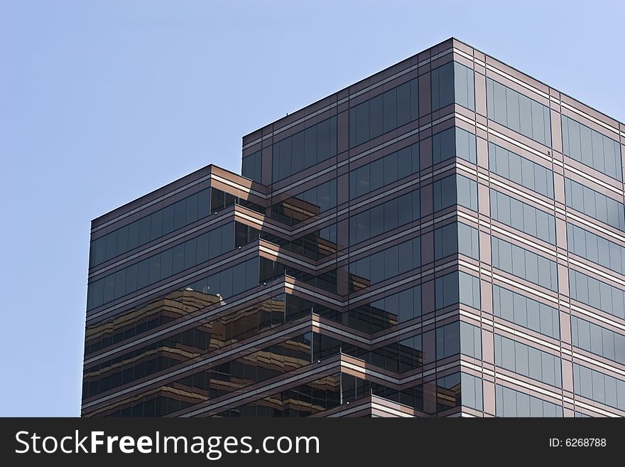 A modern brown reflective building against a blue sky. A modern brown reflective building against a blue sky