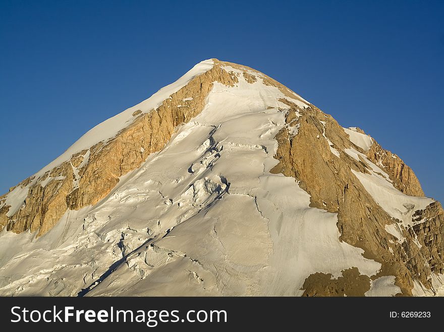 High rocky mountain peak with torn glacier