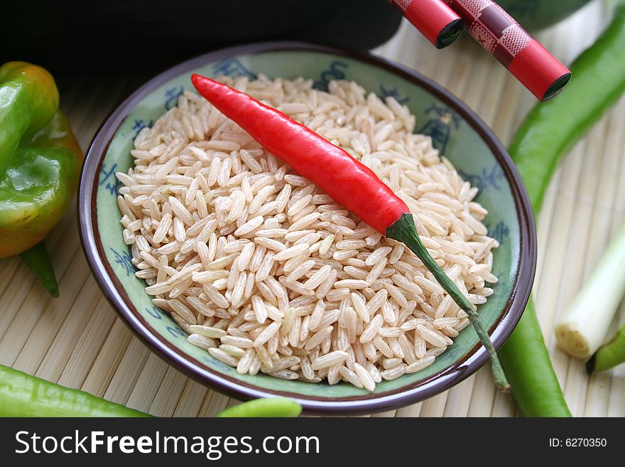 Some asian rice in a bowl with a chili