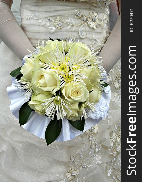 Half body portrait of bride in traditional white wedding dress holding yellow bouquet of roses. Half body portrait of bride in traditional white wedding dress holding yellow bouquet of roses.