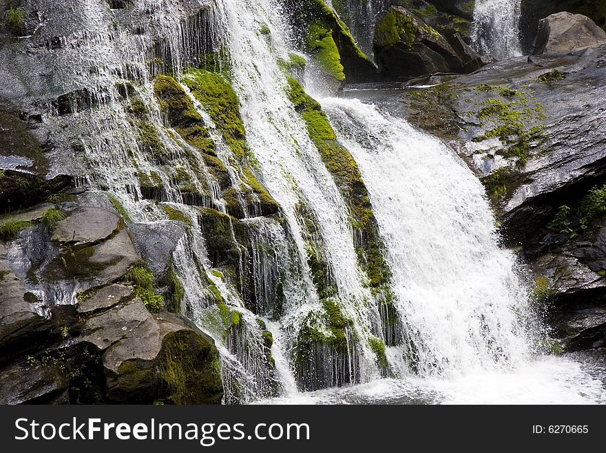 A waterfall cascading over green moss on the rocks. A waterfall cascading over green moss on the rocks