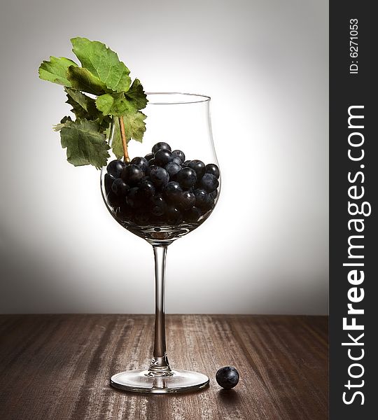 Grape berries in glass on wood table.