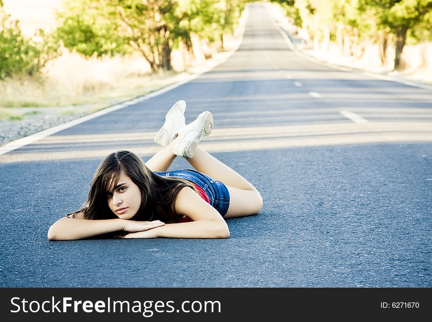 Young beautiful woman laying in the middle of the road. Young beautiful woman laying in the middle of the road