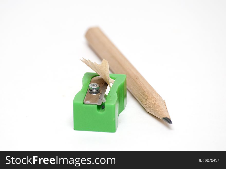 Wooden pencil besides a green plastic sharpener. Wooden pencil besides a green plastic sharpener