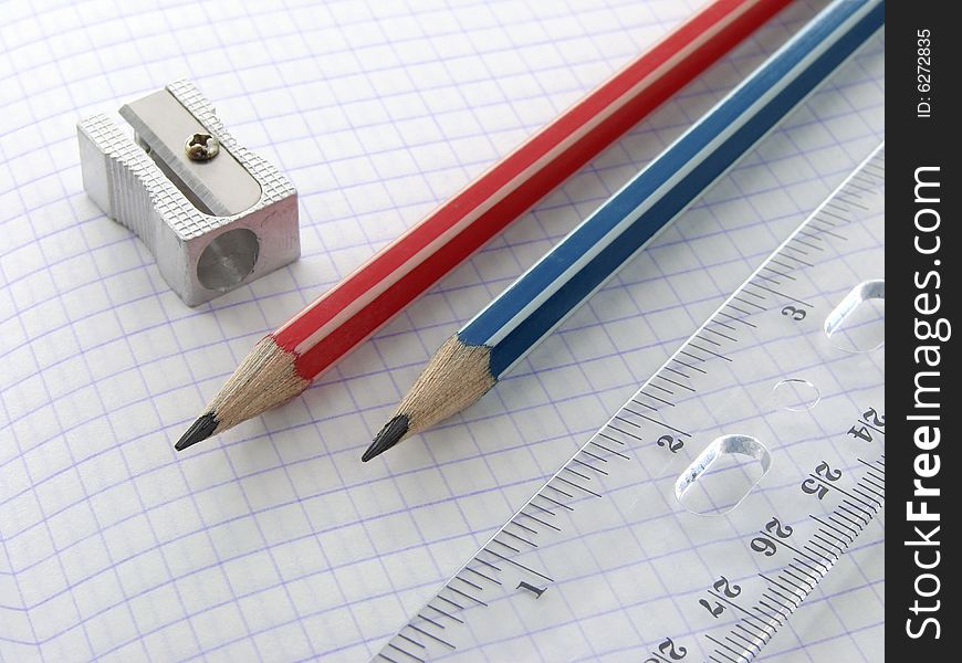 Two pencils and a ruler with sharpener on the workbook page. Two pencils and a ruler with sharpener on the workbook page