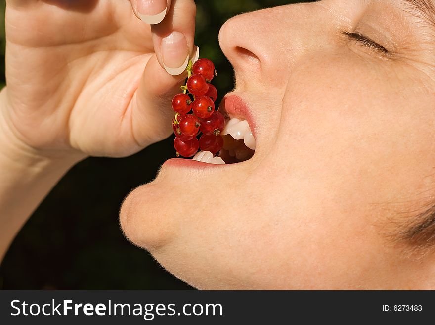 Young beautiful woman tasting redcurrant. Young beautiful woman tasting redcurrant