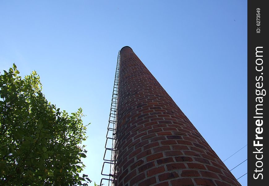 Old chimney and tree against blue sky